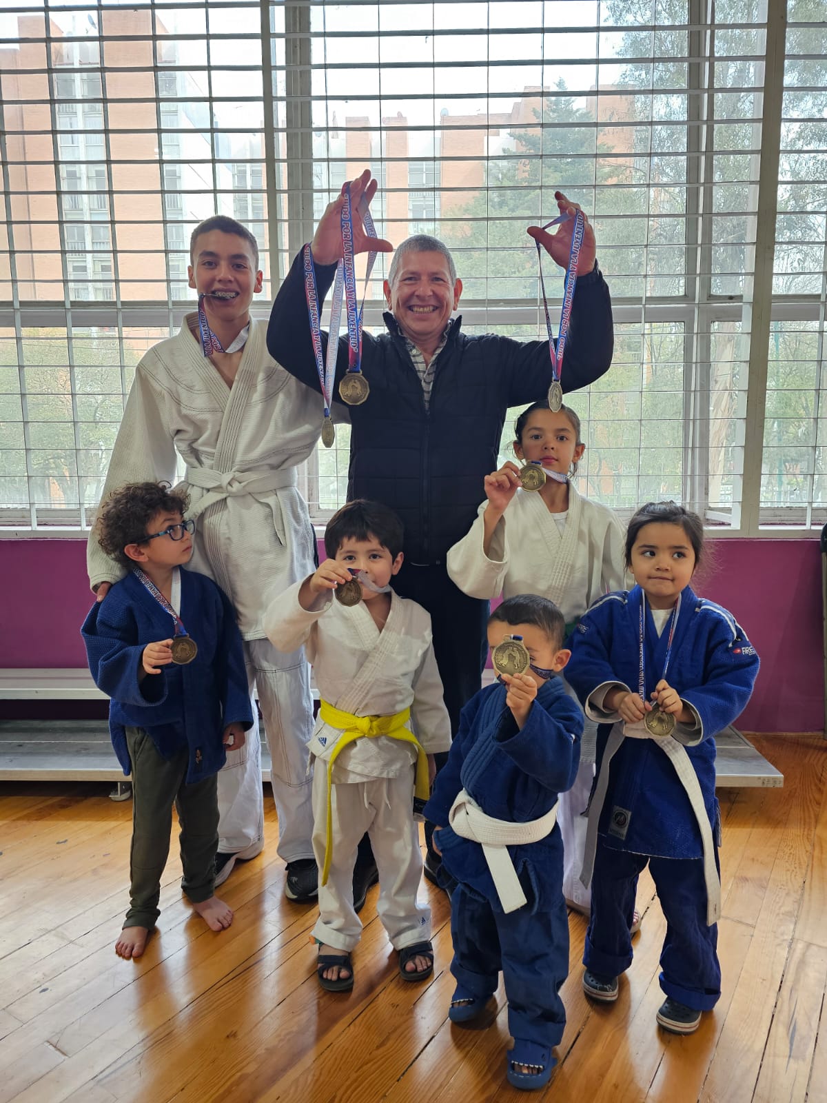 El sensei del Club de Judo ERA con sus alumnos infantiles mostrando las medallas ganadas en competencia en CDMX